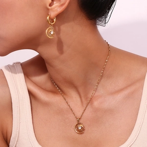 Detail of 18K gold plated moon and eye jewelry set worn by a model on a light background