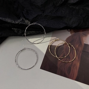 Close-up of minimalist gold and silver large hoop earrings on a magazine style background