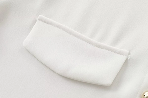 Detail of white crepe shirt showing neat stitching on shoulder pad and flap pocket