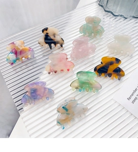 Macro shot of 9 colorful acetate mini hair claws in various marble and floral patterns
