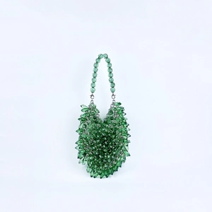 Detailed close-up of handmade green faceted crystal beads on a stylish evening handbag