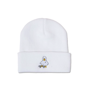 Détail d'un bonnet en tricot blanc avec canard brodé sur un skateboard tendance