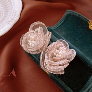 Detailed close-up of champagne mesh flower earrings with pearls on dark velvet