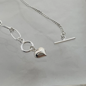 Close-up of 925 sterling silver heart anklet with OT clasp on marble surface