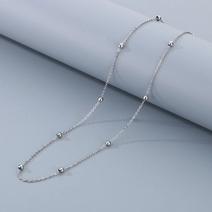 Detail shot of a minimalist silver stainless steel bead chain necklace on a display stand