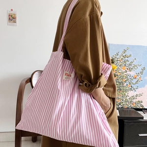Dettaglio della grande borsa tote in tela a righe rosa con etichetta in tessuto