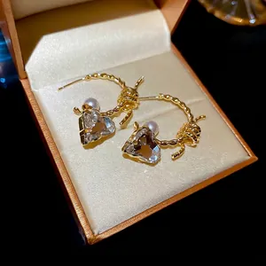 Elegant C-shaped heart earrings with pearls and crystals in a luxury jewelry box