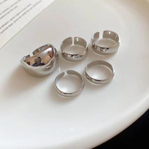 Five-piece set of silver geometric irregular open rings displayed on a white plate