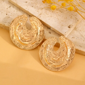 Detail view of gold textured earrings with hammered metal surface on a stone tray