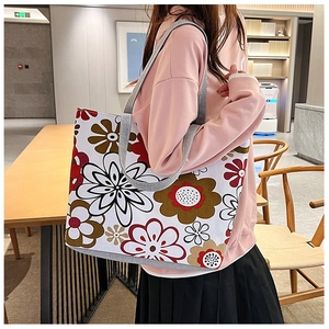 Detail of canvas tote bag showing artistic large floral print and wide gray handles