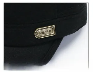 Detail of black wool texture and vintage bronze metal emblem on the earflap flat cap