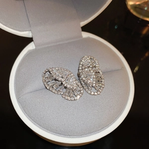 Macro shot of silver zircon butterfly earrings on a gray velvet jewelry box lining