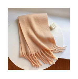 Detail of soft peach mohair scarf with fringe tassels on white decorative tray