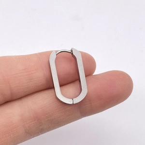 Close-up of a silver U-shaped stainless steel geometric hoop earring held by hand