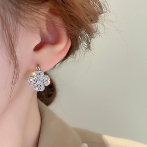 Macro shot of silver four-leaf clover earrings with sparkling zircon stones