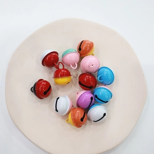 Mix of colorful 2.2cm metal bells on a beige plate for DIY Christmas keychain crafts