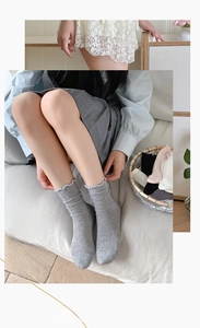 Detail of ruffled lace trim and ribbed texture on grey cotton mid-calf socks