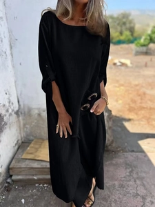 Detail of loose black long dress with round neck and metal buckle on breathable fabric