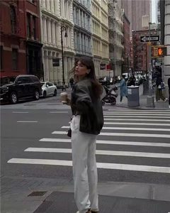 Stile street con giacca di pelle vintage oversize e pantaloni bianchi a gamba larga