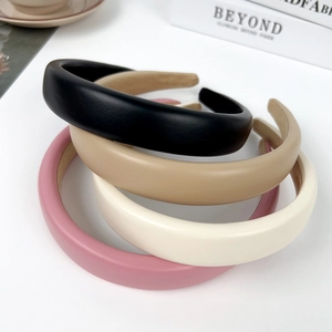 Minimalist wide solid color sponge headbands in four colors on a white tabletop