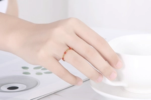 Dettaglio ravvicinato di un anello a catena dorata con piccole perline di resina rossa