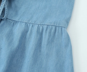 Détail du tissu denim bleu clair avec plis précis à la taille et texture de couture