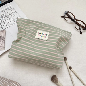Detail of green and pink striped toiletry bag with soft fabric texture and logo label