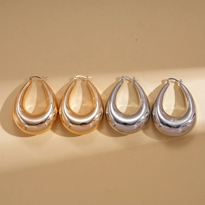 Polished gold and silver hollow teardrop hoop earrings for women on a textured background