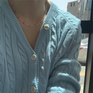 Blue cable-knit V-neck cardigan with white buttons and classic textured patterns