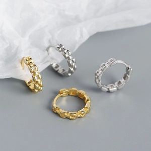 Detail view of gold and silver S925 earrings with geometric metal strap texture design