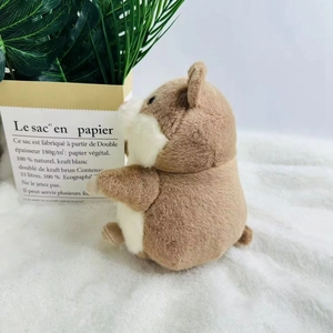 Close-up of fluffy brown and white hamster plush toy on a soft white carpet