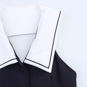 Detail of sailor collar on a sleeveless black top with white contrast trim and buttons