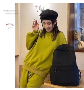 Detail view of a black minimalist backpack paired with a green casual sweatshirt set