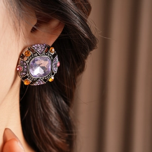 Close-up of vintage baroque square earring with purple crystals and orange accents