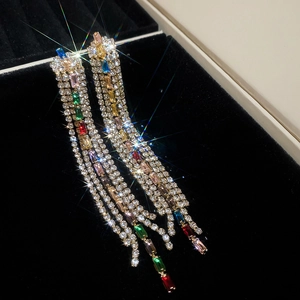Macro shot of long fringe earrings with colorful square gems and sparkling zircons