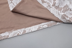 Detail of khaki smooth fabric with intricate white lace trim on the dress hemline