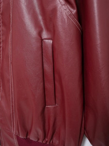 Detail of burgundy leather jacket featuring white contrast stitching and side pockets