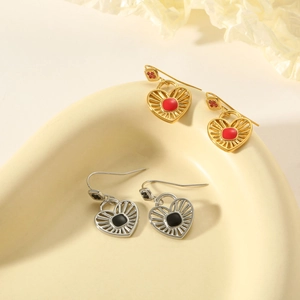 Gros plan de boucles d'oreilles cœur avec gemmes rouges et noires sur plateau beige