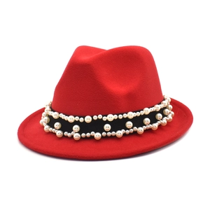 Close-up of red wool fedora hat featuring elegant faux pearl embellishments on black band