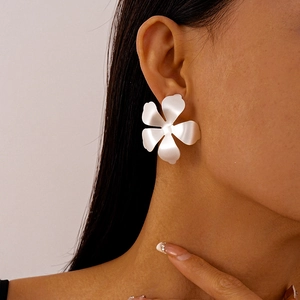 Close-up of a large matte white flower stud earring worn by a model in profile