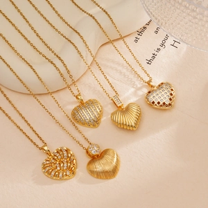 Five gold-plated heart pendant necklaces with zircons displayed on a beige background