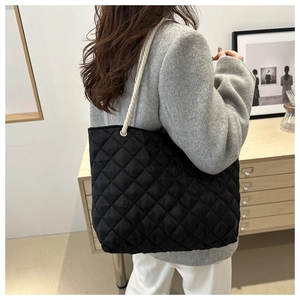 Détail du cabas en nylon noir matelassé avec des poignées en corde tressée blanche