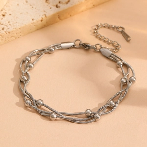 Vue détaillée d'un bracelet triple couche à chaîne serpent argentée avec perles