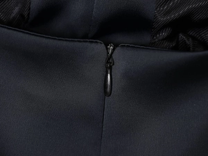 Détail de la fermeture éclair invisible sur la mini robe en satin noir chic
