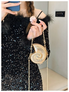 Detailed close-up of golden conch-shaped evening bag with pearly crossbody chain strap