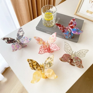 Elegant acetate butterfly hair claws in five colors on a bright minimalist table