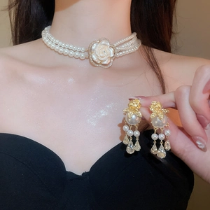 Detail of vintage multilayer pearl choker and floral earrings with gold accents