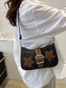 Detail of vintage denim baguette bag with star patches and brown leather strap