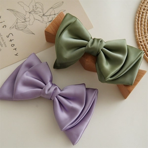 Detailed shot of olive green and lilac satin bow hair clips with silky texture