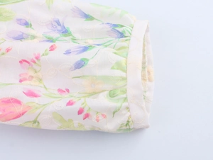 Detail of lantern sleeves with floral embroidery and pleated cuffs on a cream dress